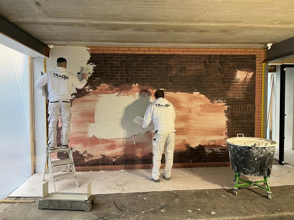 Stukadoor van Trad aan het werk op een wand